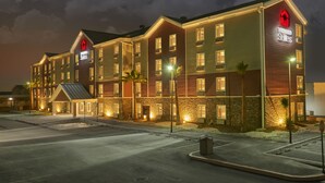Un hotel de varios pisos con una entrada destacada, un área de espera cubierta y una fachada bien iluminada.