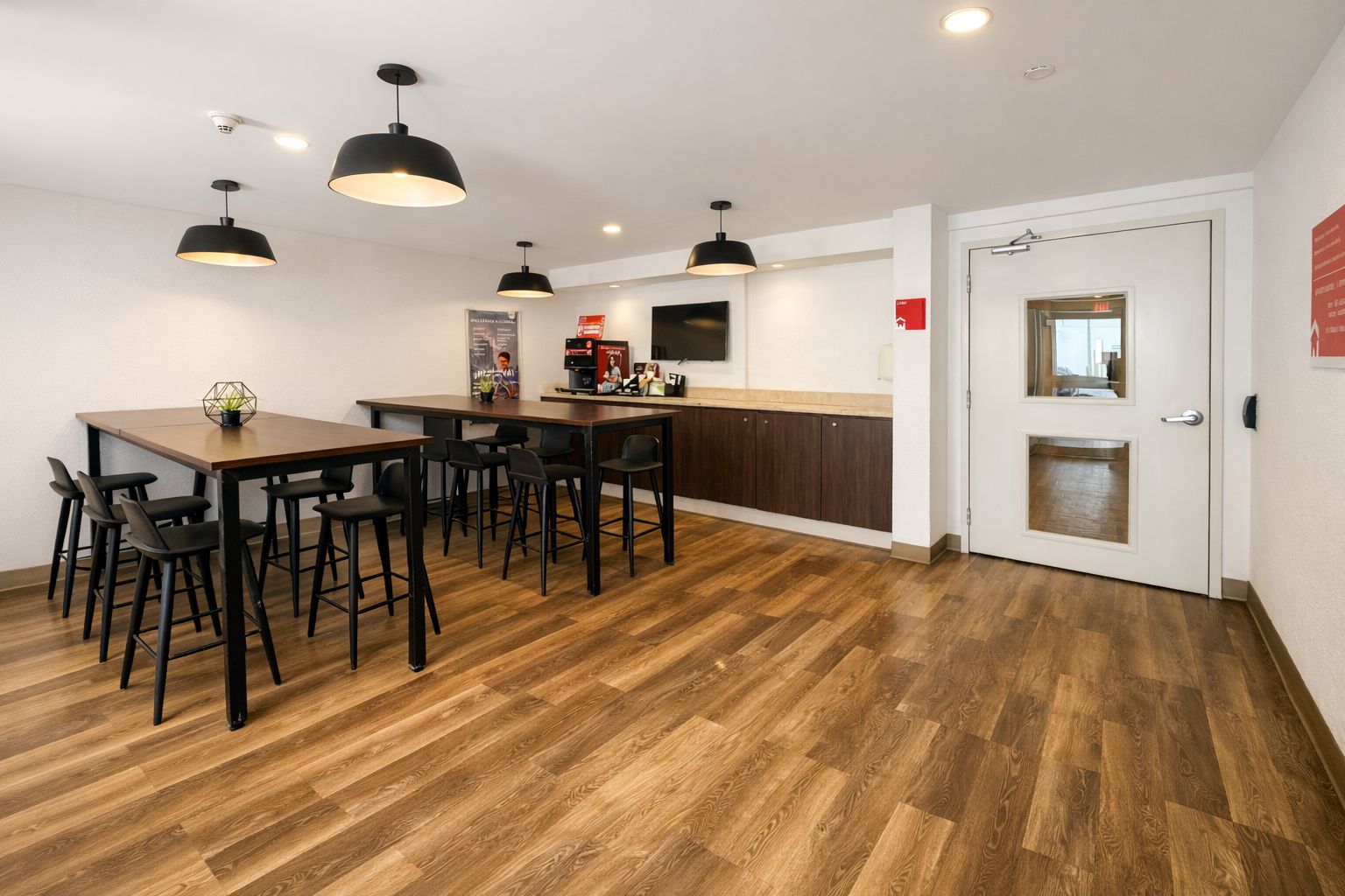 A modern kitchen with a dining area, wooden flooring, and pendant lighting.