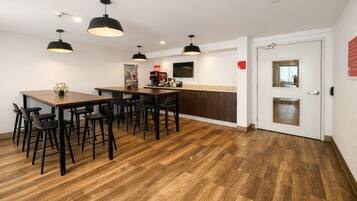 A modern kitchen with a dining area, wooden flooring, and pendant lighting.