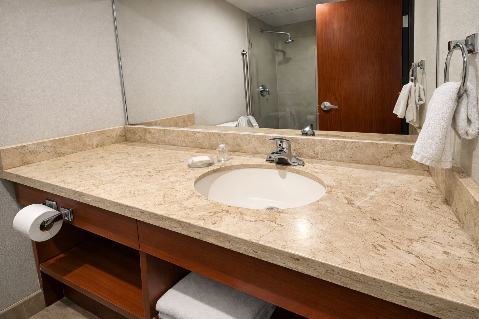 Un baño con lavamanos de mármol, un espejo, toallero y ducha.