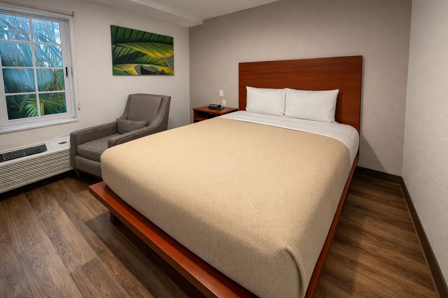 Ein Hotelzimmer mit Bett, Sessel, Nachttisch, Heizung und Fenster mit Blick auf Palmen.
