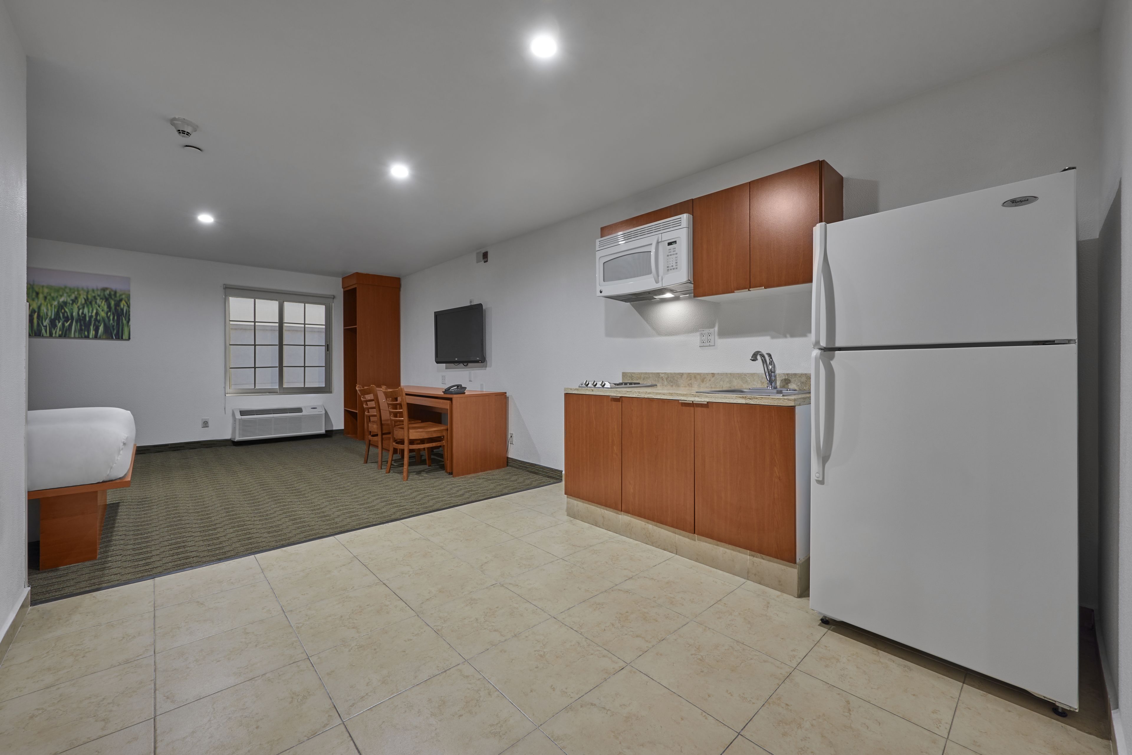 Una cocina moderna con microondas, refrigerador y armarios de madera.