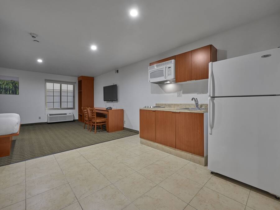 Una cocina moderna con microondas, refrigerador y armarios de madera.