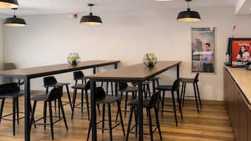 Un moderno comedor con una mesa larga y varias sillas, iluminación en el techo y un cartel en la pared.