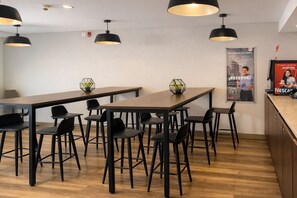 Un moderno comedor con una mesa larga y varias sillas, iluminación en el techo y un cartel en la pared.