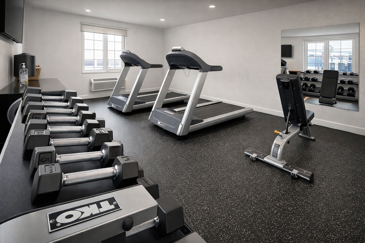 A gym with treadmills, dumbbells, and weight machines.
