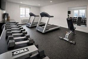 Un gimnasio con cintas de correr, mancuernas y máquinas de pesas.