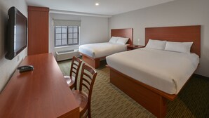 Una habitación de hotel con cama, escritorio, silla, televisión y ventana.