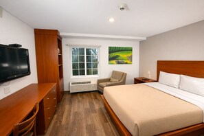 A hotel room with a bed, a television, a chair, a window, and a wall-mounted artwork. - Extended Suites Monterrey Aeropuerto (Apodaca)