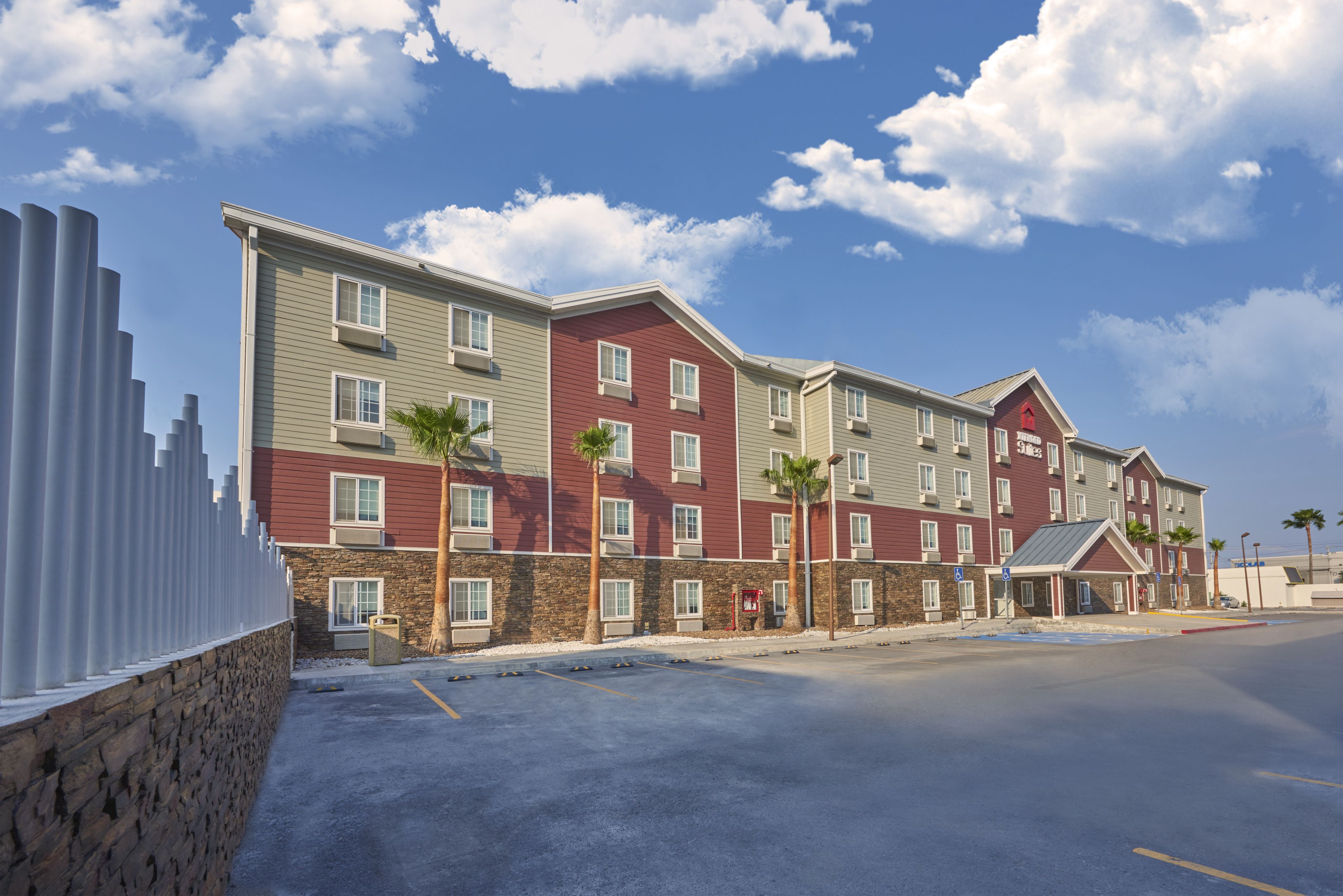 Ein mehrstöckiges Hotel mit Stein-Fassade, zahlreichen Fenstern und einem Parkplatz.