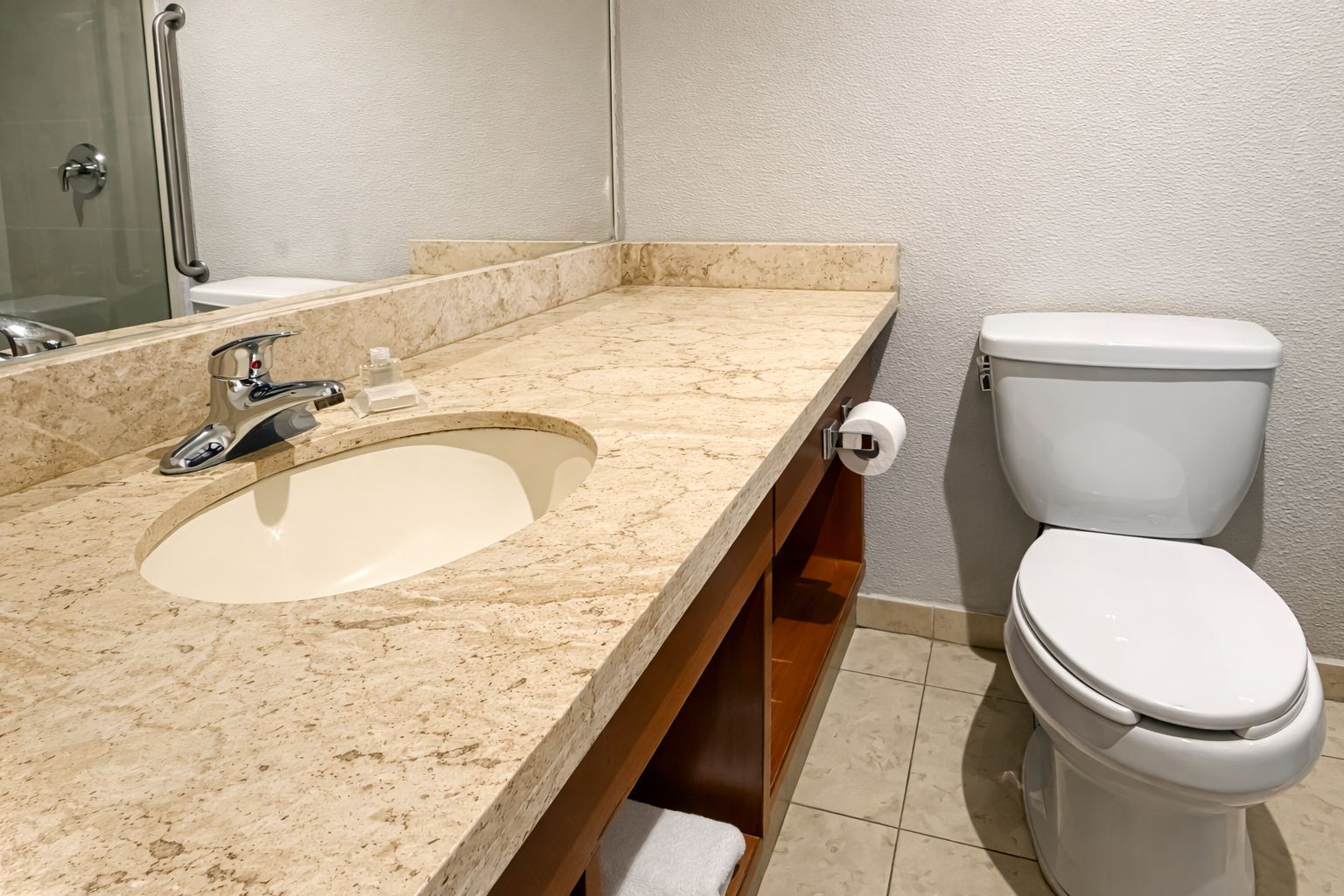 Une salle de bain avec un lavabo en marbre, des toilettes et une douche à parois de verre.