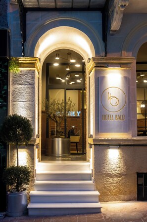 A hotel entrance with a sign reading 'HOTEL BALO,' a staircase leading inside, and a potted plant to the left. - Balo (Istanbul)