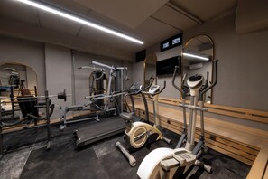 Ett gym med träningsutrustning, speglar och en tv.