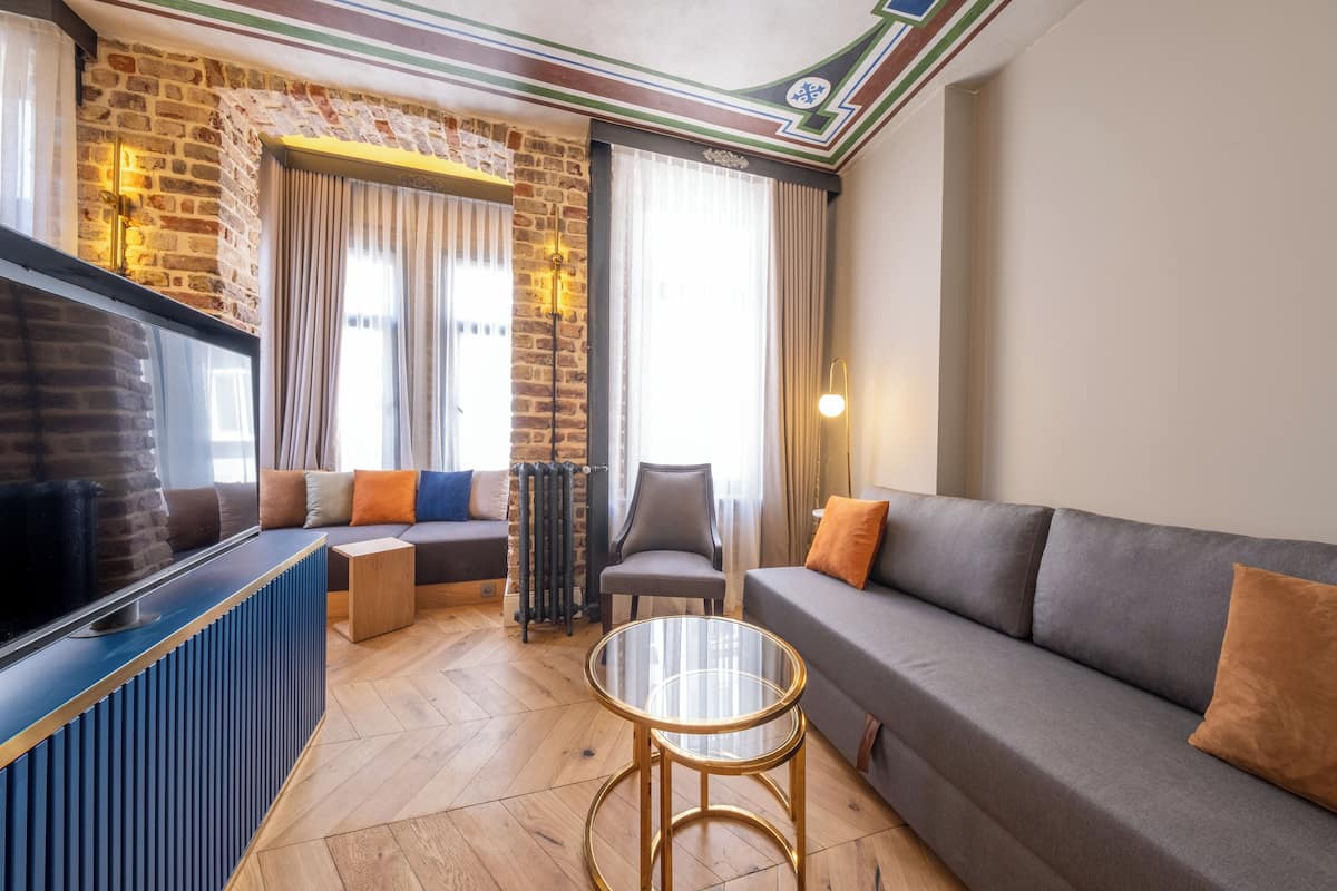 A modern living room with a brick wall, a sofa, a glass coffee table, and a TV.