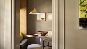 Un intérieur moderne avec un plancher en bois, une table ronde sur laquelle se trouvent un bol et une tasse, un banc et une suspension lumineuse.