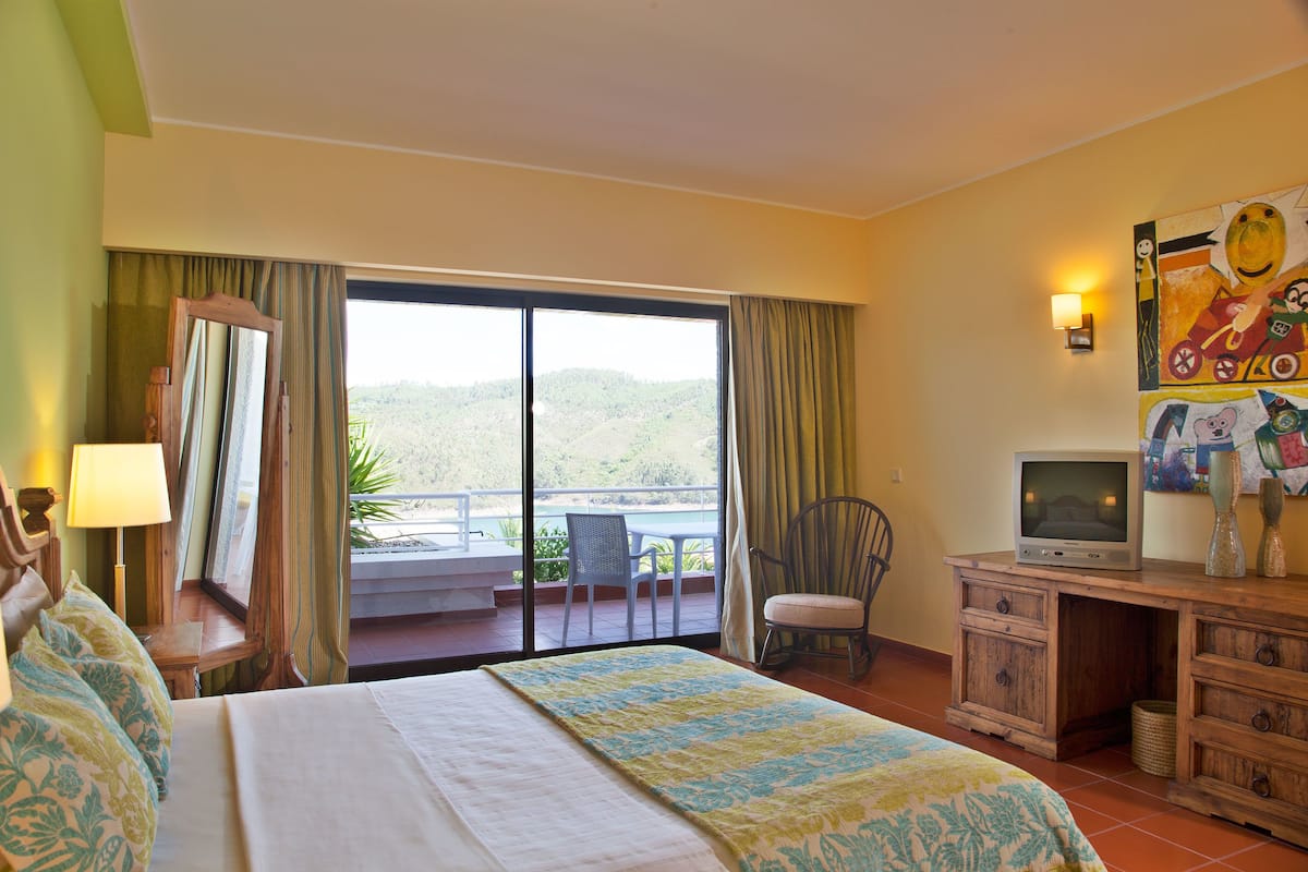 A hotel room with a bed, a television, a desk, and a chair.