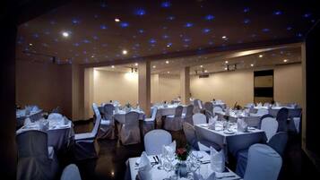 A banquet hall with round tables, white tablecloths, and chairs.