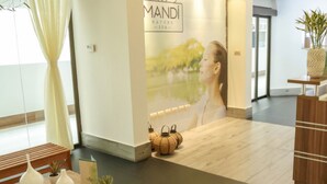 A reception area with a wooden table, vases, and a wall with a logo and a large poster.