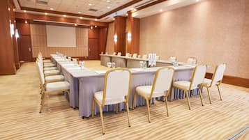 A conference room with a long table, chairs, and a projector screen.