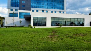 A modern building with a large glass facade, a flat roof, and a well-maintained lawn in front. - Park Dedeman Denizli (Denizli)