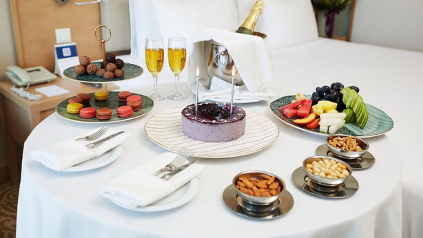 A breakfast setup with a cake, fruits, and pastries on a round table. - Park Dedeman Denizli (Denizli)