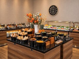 A buffet setup with various food items and a clock on the wall.