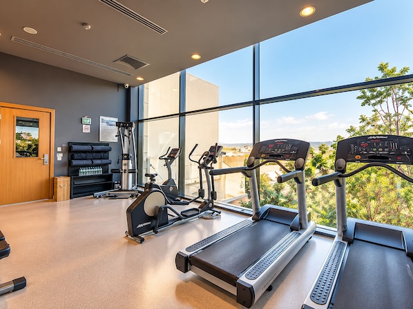 A gym with treadmills, exercise bikes, and weight machines, large windows, and a view of the outdoors. - Park Dedeman Denizli (Denizli)