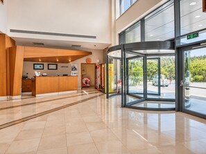 A hotel reception area with a wooden reception desk, a reception sign, and a glass door leading outside. - Park Dedeman Denizli (Denizli)
