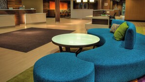 Een moderne hotellobby met een receptiebalie, zithoek en een bar.