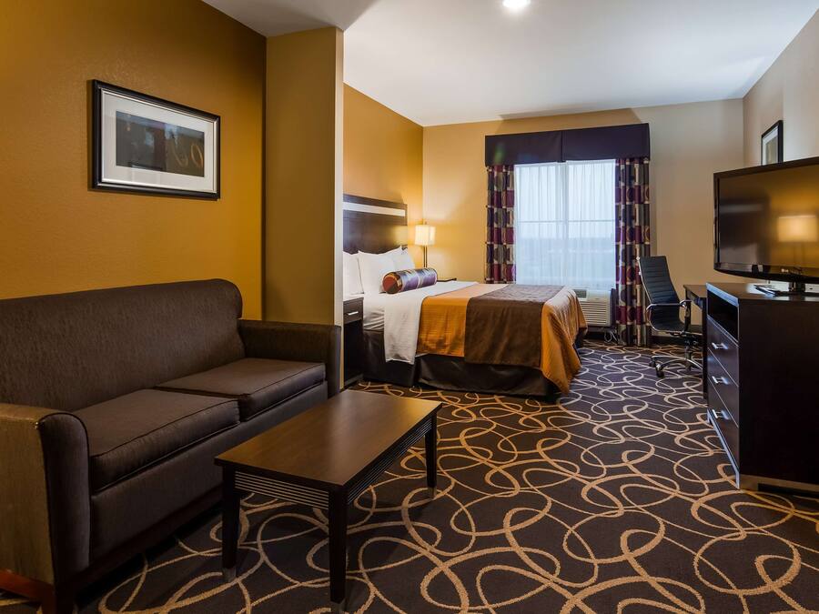 Una habitación de hotel con sofá, cama, escritorio y televisor.