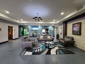 A spacious lobby with a modern chandelier, comfortable seating, a reception desk, and a digital display. - Best Western Plus Kenedy Inn (Kenedy)
