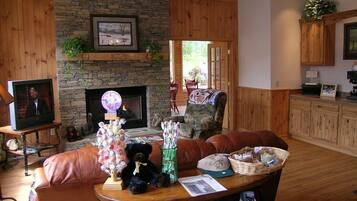 A cozy living room with a stone fireplace, leather furniture, and a television.