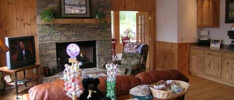 A cozy living room with a stone fireplace, leather furniture, and a television.