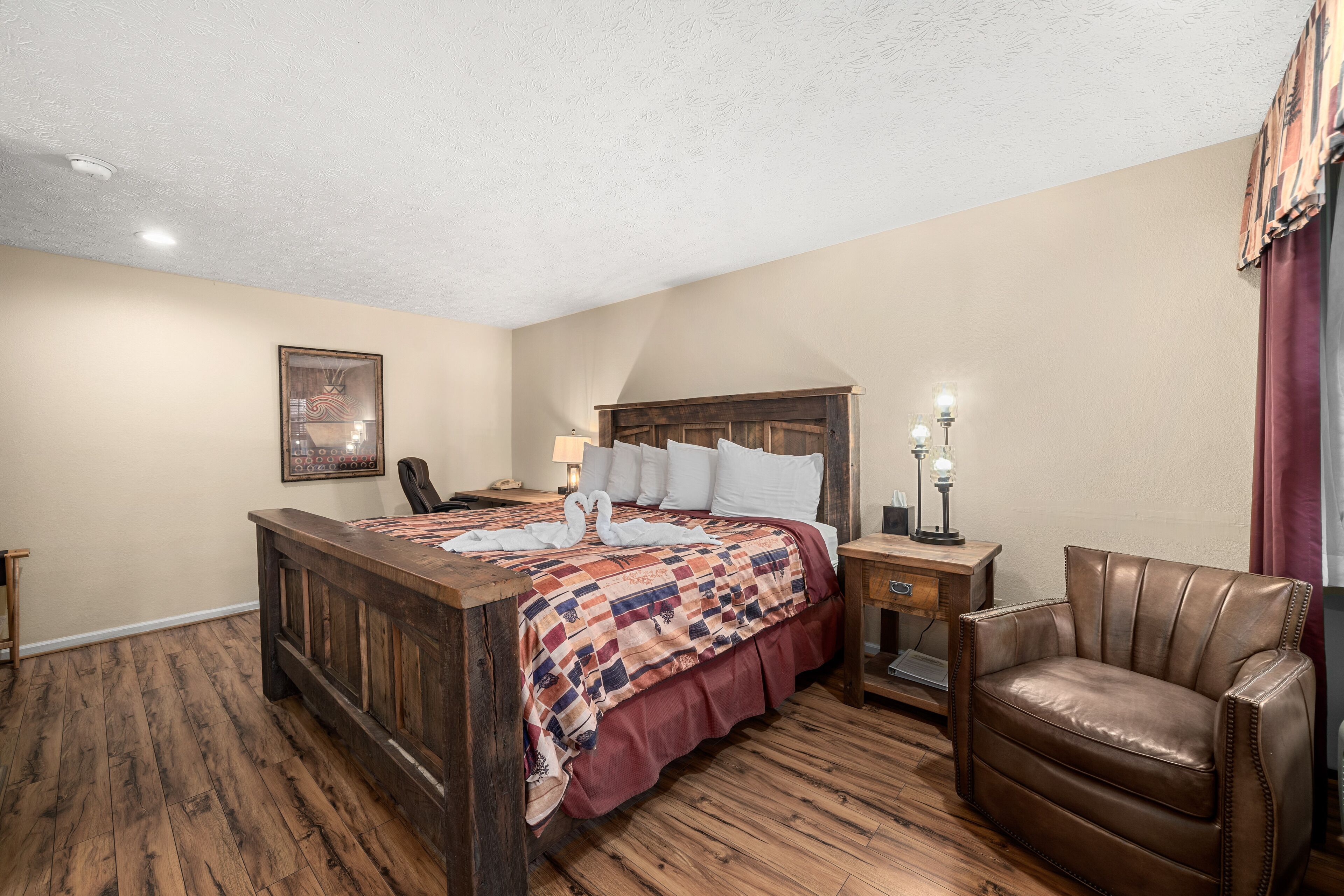 A bedroom with a wooden bed, a leather chair, a nightstand with a lamp, and a framed picture on the wall.