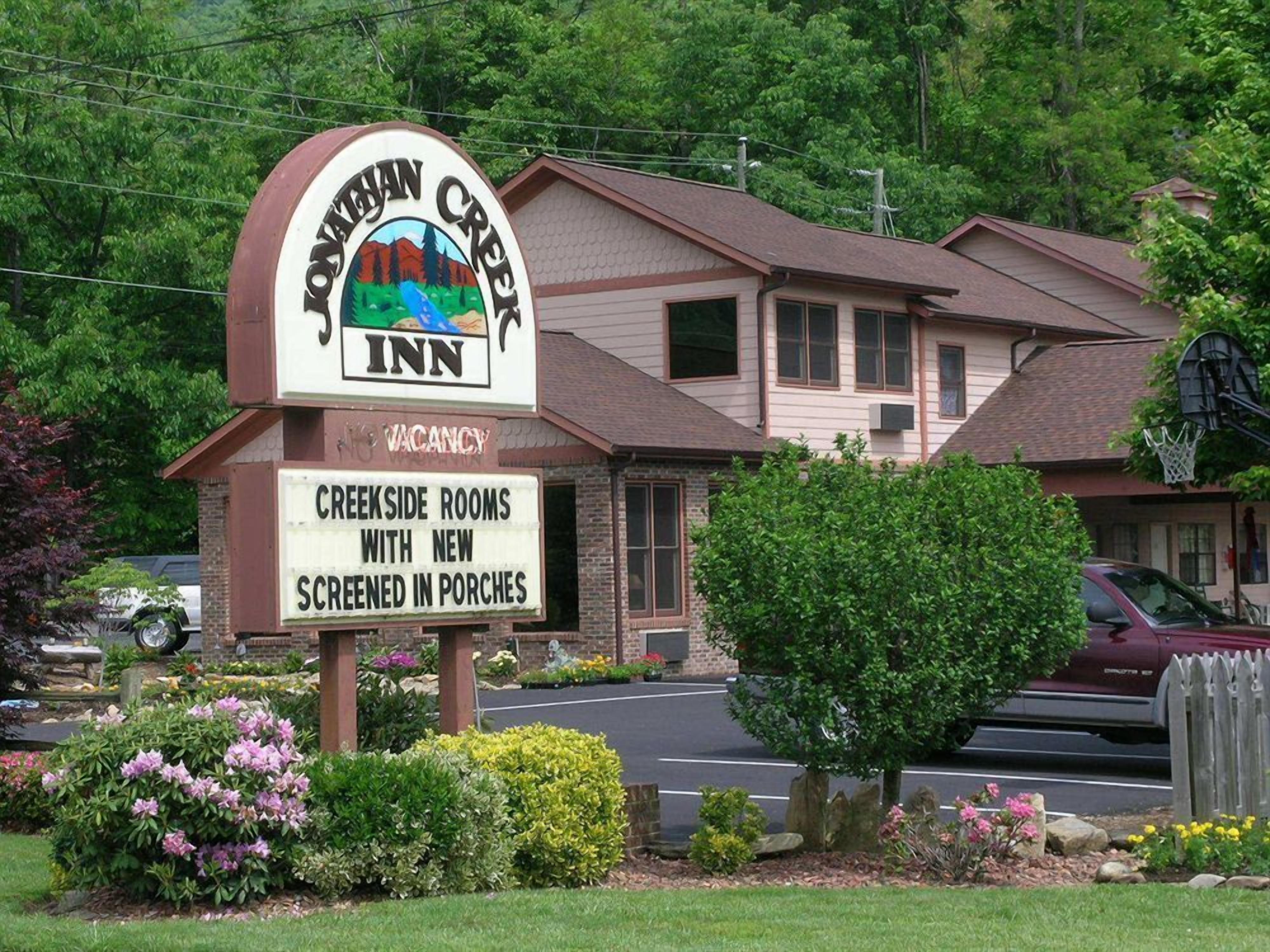 A motel sign with a mountain landscape and a message about new screened rooms.