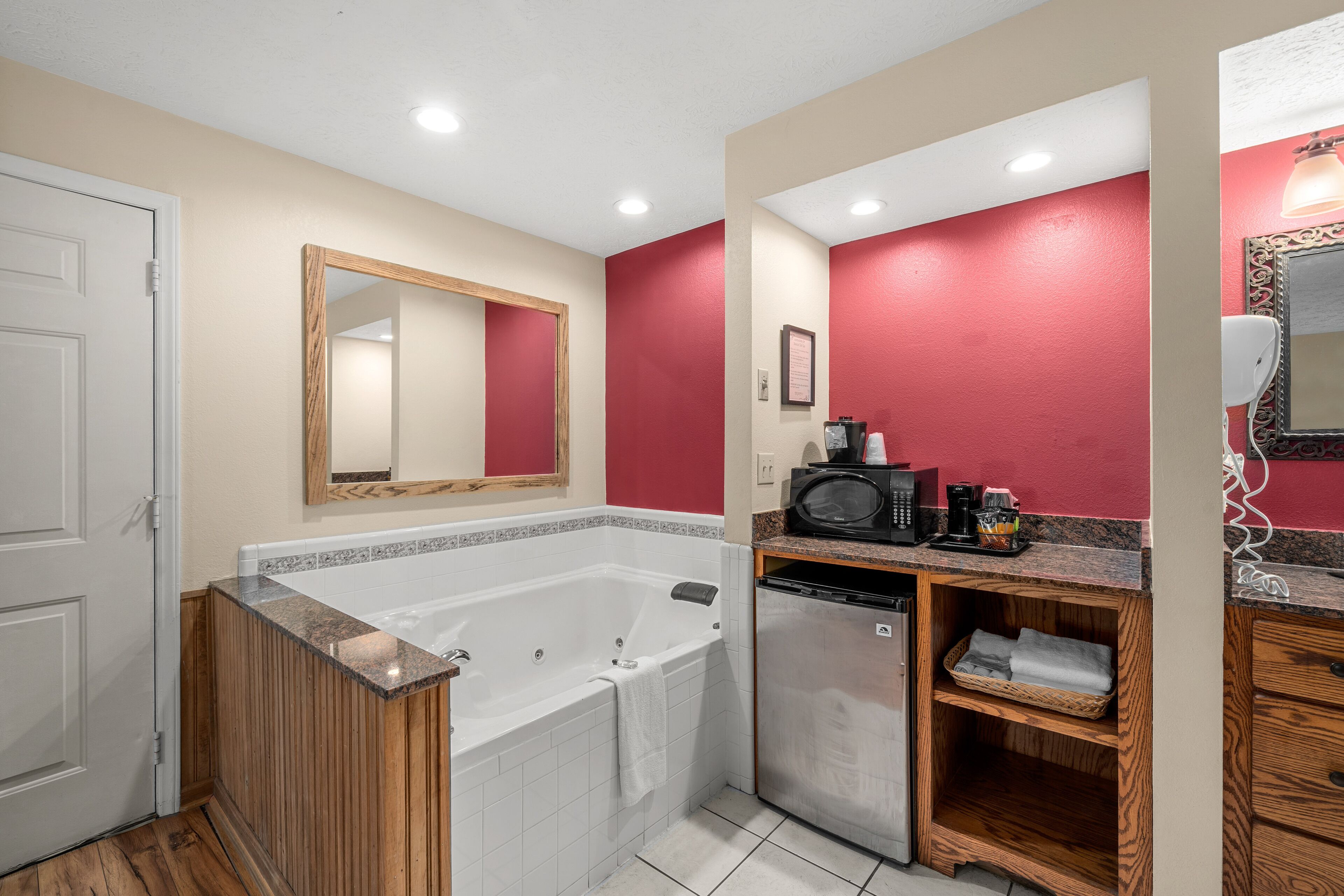 A bathroom with a bathtub, a microwave, and a coffee maker on the countertop.