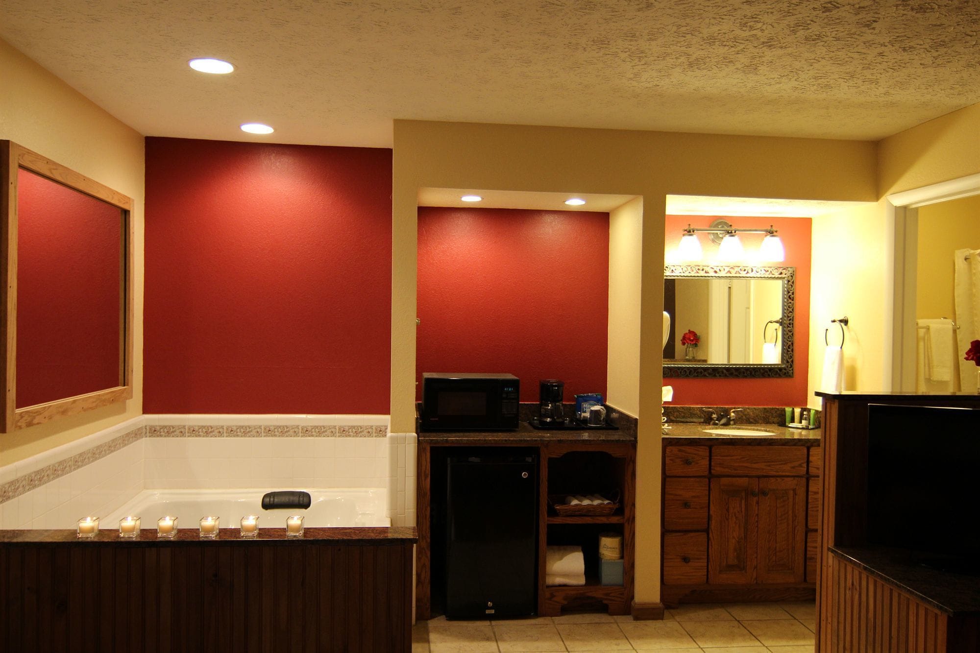 A bathroom with a bathtub, a vanity with a mirror, and a microwave on the counter.