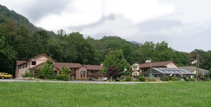 Um motel com uma placa grande, um estacionamento e um gramado na frente.