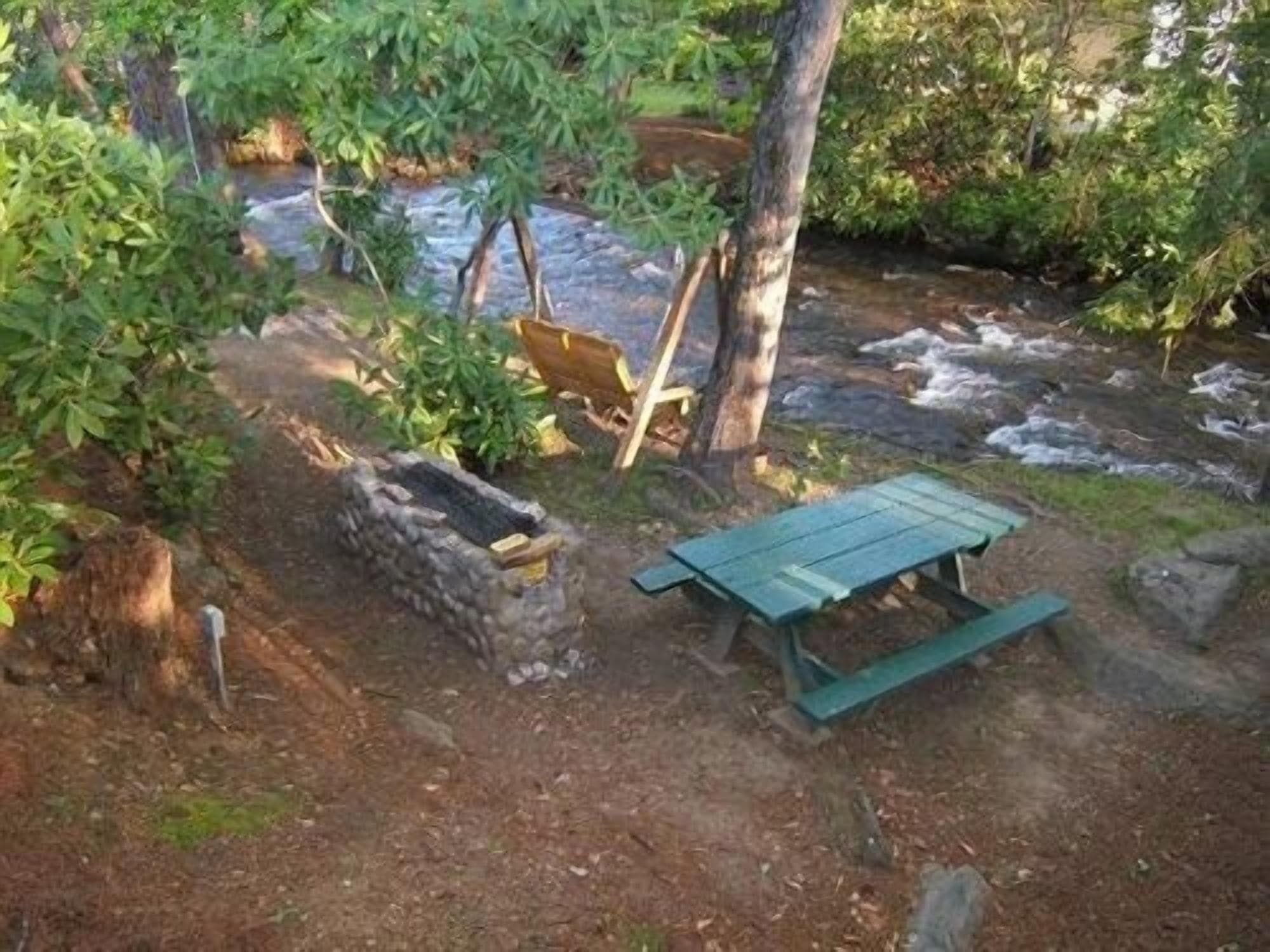 A rustic outdoor setting with a wooden bench, a stone wall, and a small stream.