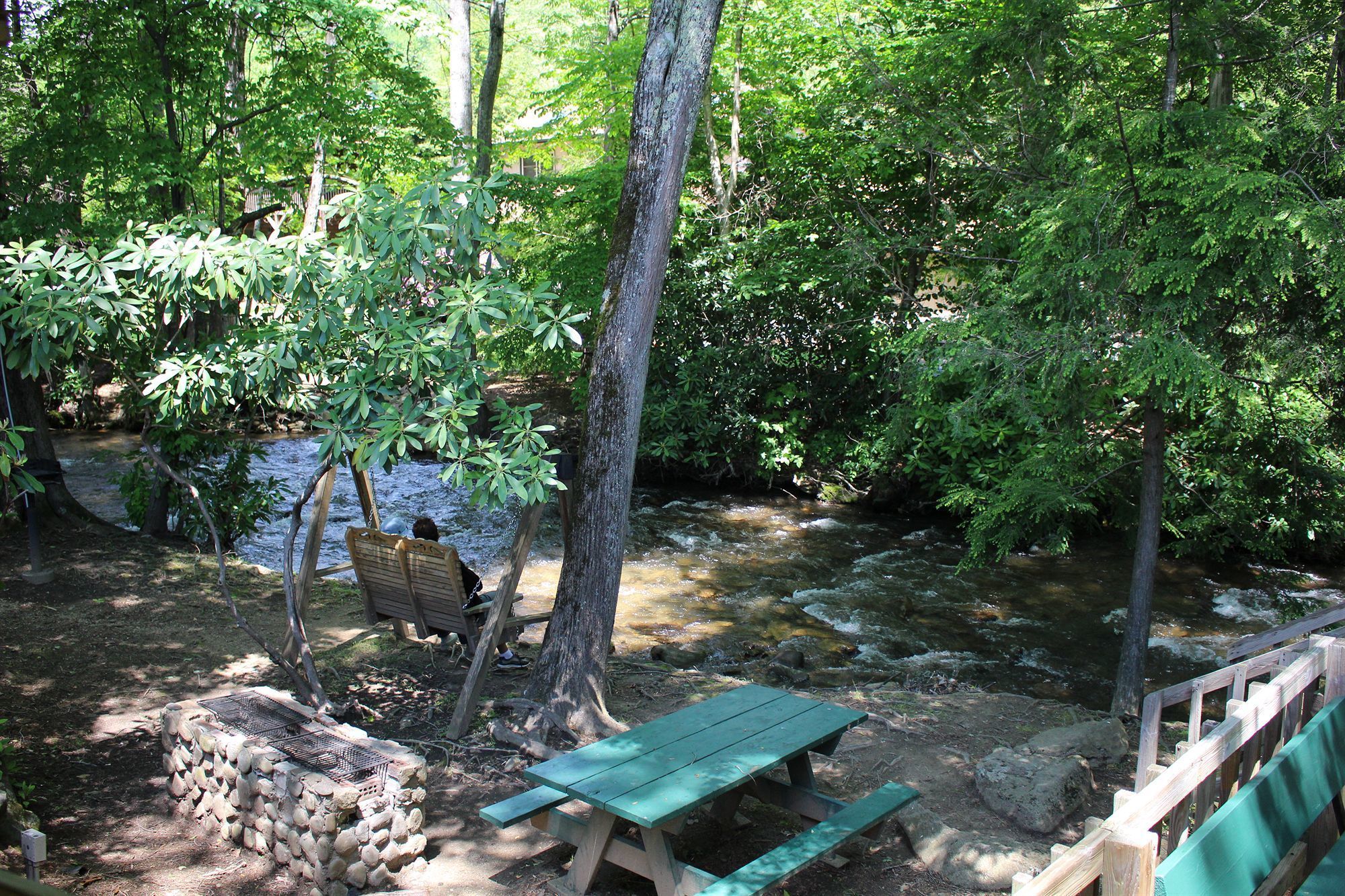 A picnic area with a wooden bench and a stone fire pit.