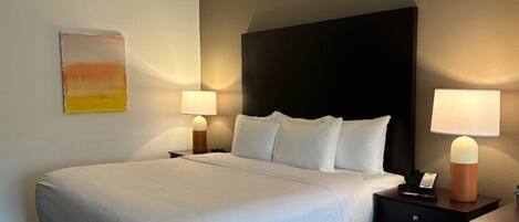 Une chambre d’hôtel avec un grand lit, deux tables de chevet et un tableau au mur.