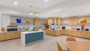A modern kitchen with wooden cabinets, a central island, and various appliances. - Comfort Inn & Suites Verona at Turning Stone Resort Casino (Verona)