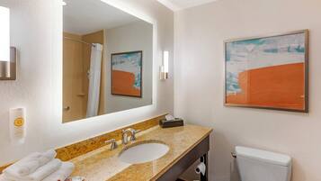 A bathroom with a sink, mirror, towel rack, toilet, and a framed abstract painting on the wall.