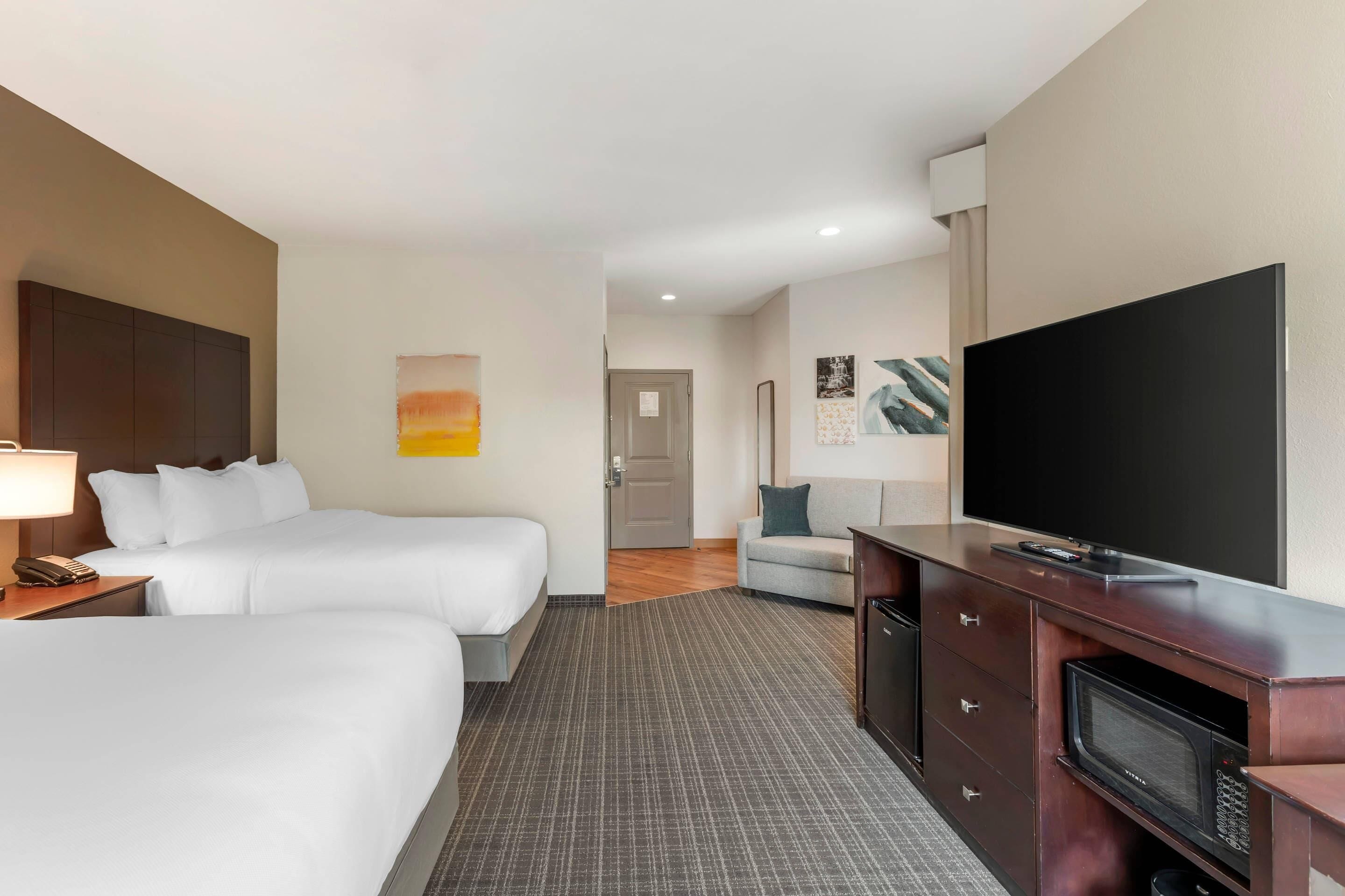 Quarto de hotel com duas camas, televisão, escrivaninha e micro-ondas.