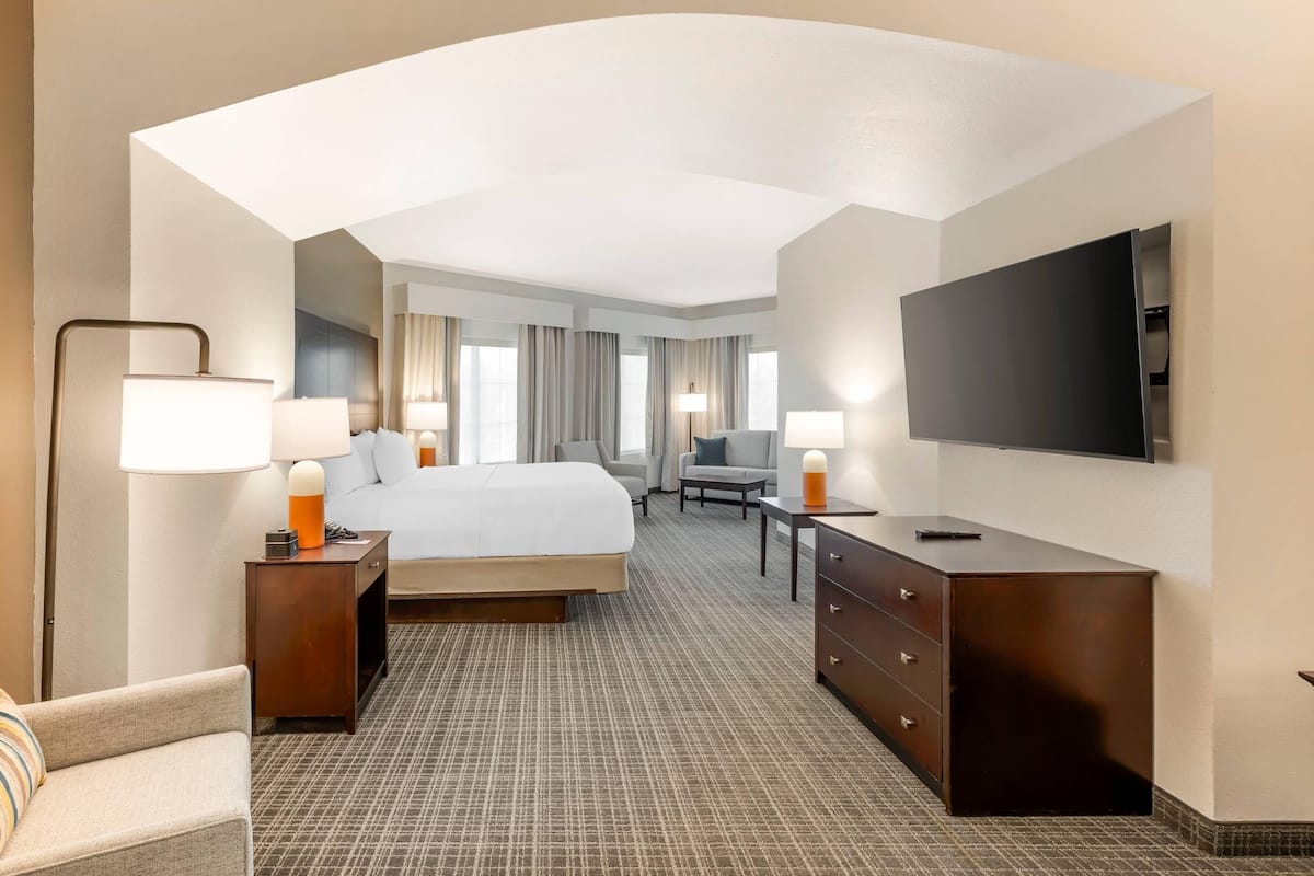 Habitación de hotel con cama, escritorio, silla, televisor y lámpara.