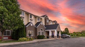 A multi-story building with a covered parking area, a driveway, and a tree in the foreground. - Sleep Inn & Suites Kalamazoo Southwest (Kalamazoo)