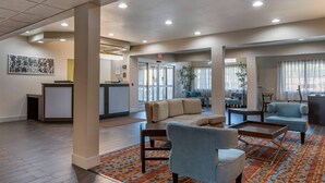A hotel lobby with a reception desk, seating area, and large windows.