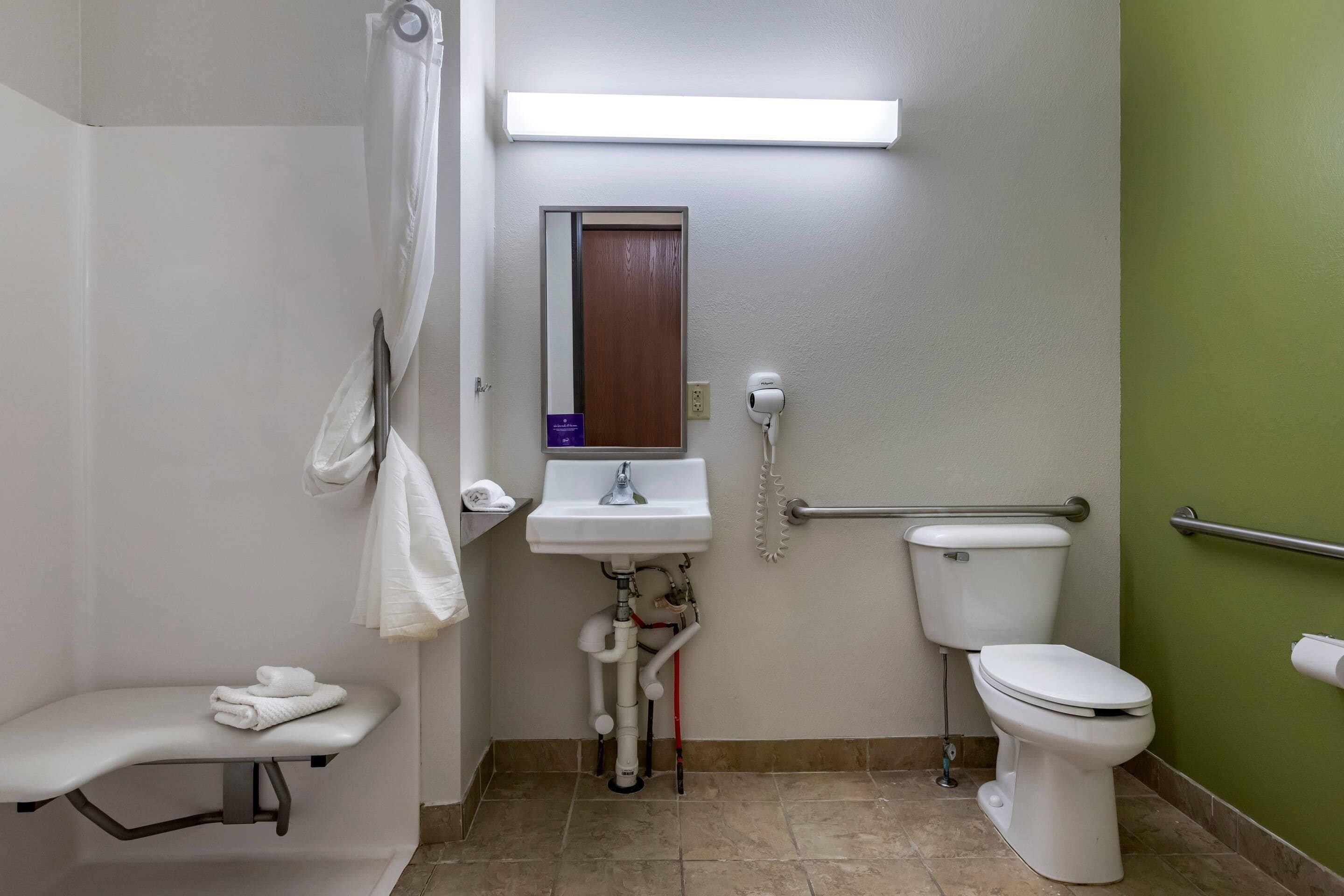 Bagno con lavandino, water, doccia e maniglia di sostegno.