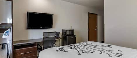 Habitación de hotel con cama, escritorio con computadora, televisor, microondas y cafetera.