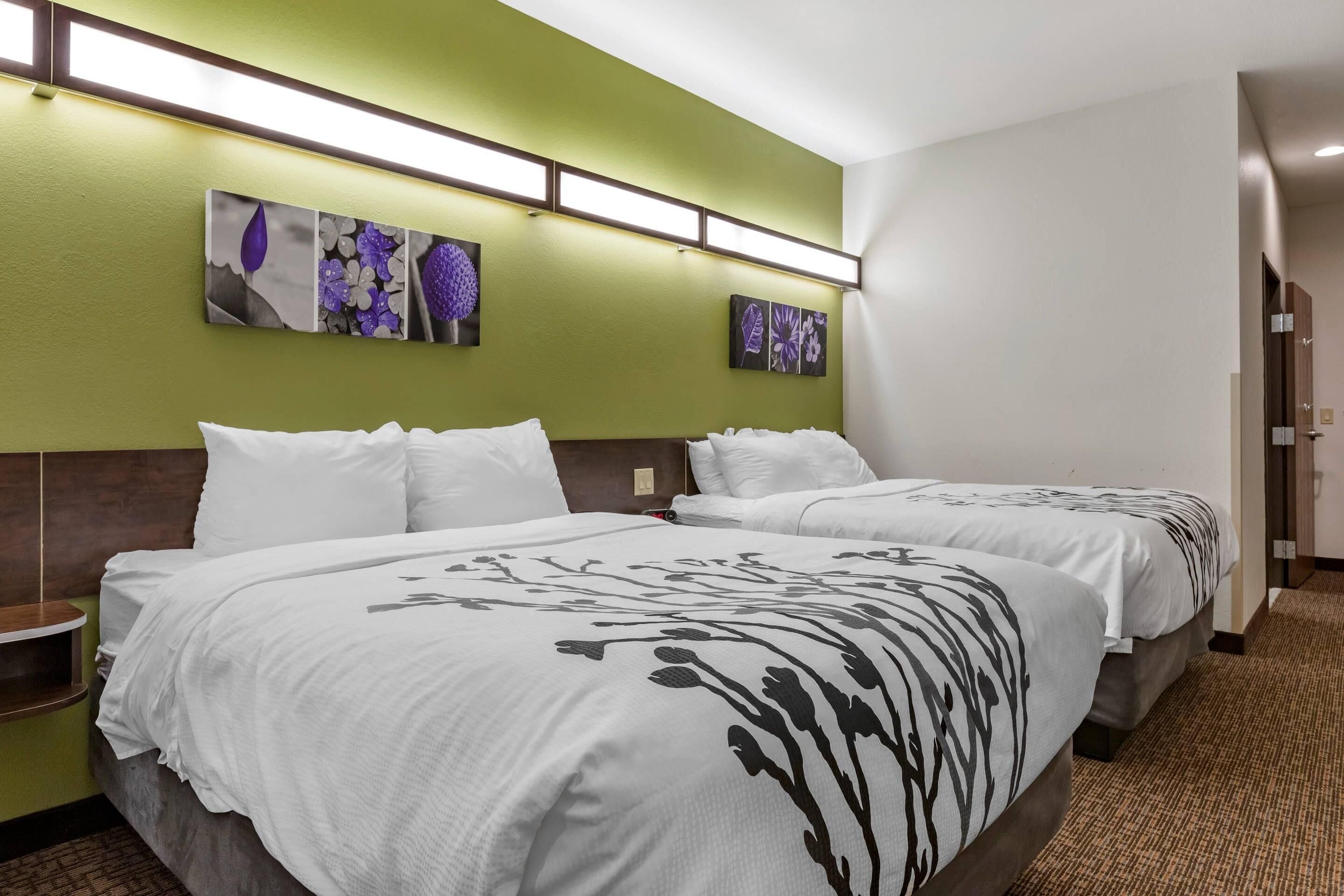 Een hotelkamer met twee bedden, groene wanden en een kunstwerk aan de muur.